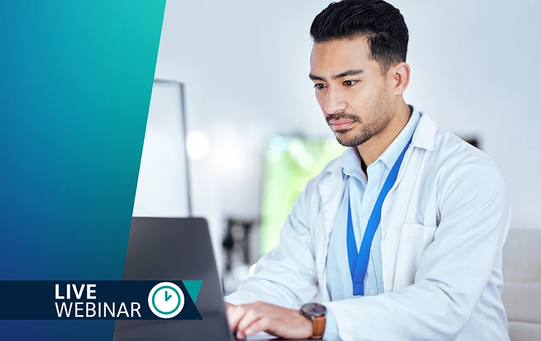 Male dental professional sitting at a desk, typing on a laptop computer