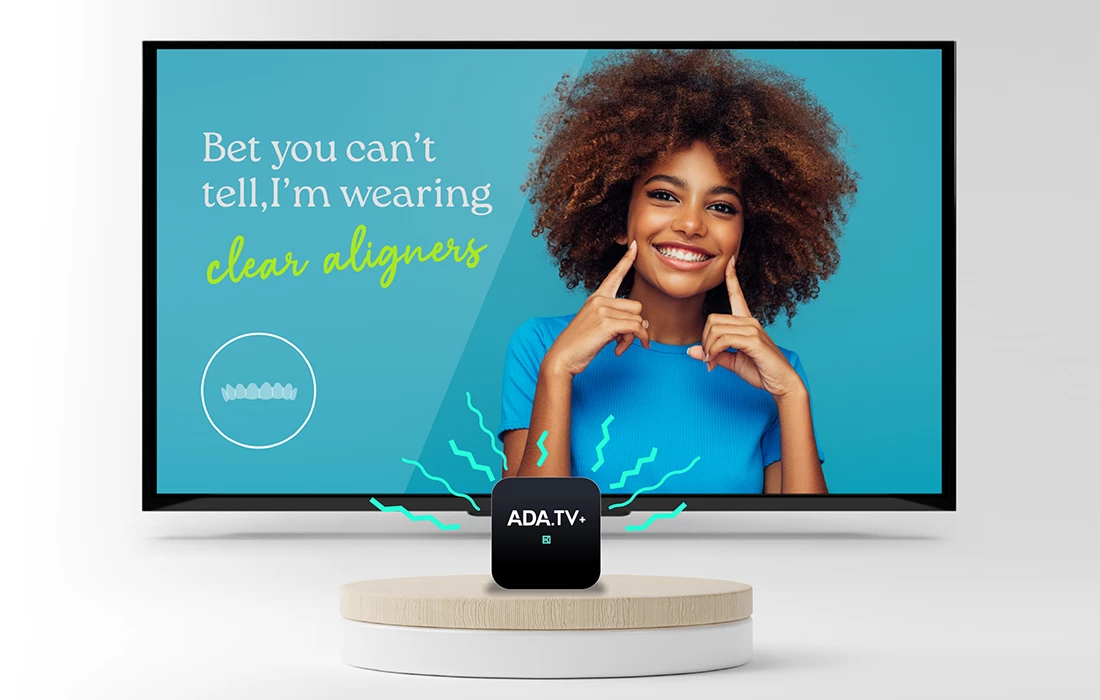 Television displaying ADA TV+ content, smiling woman pointing to her dental aligners