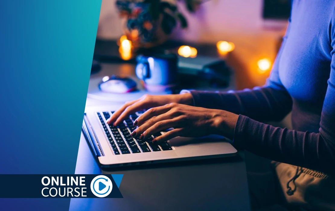 Hands typing on a laptop keypad in a dark room with warm light bulbs